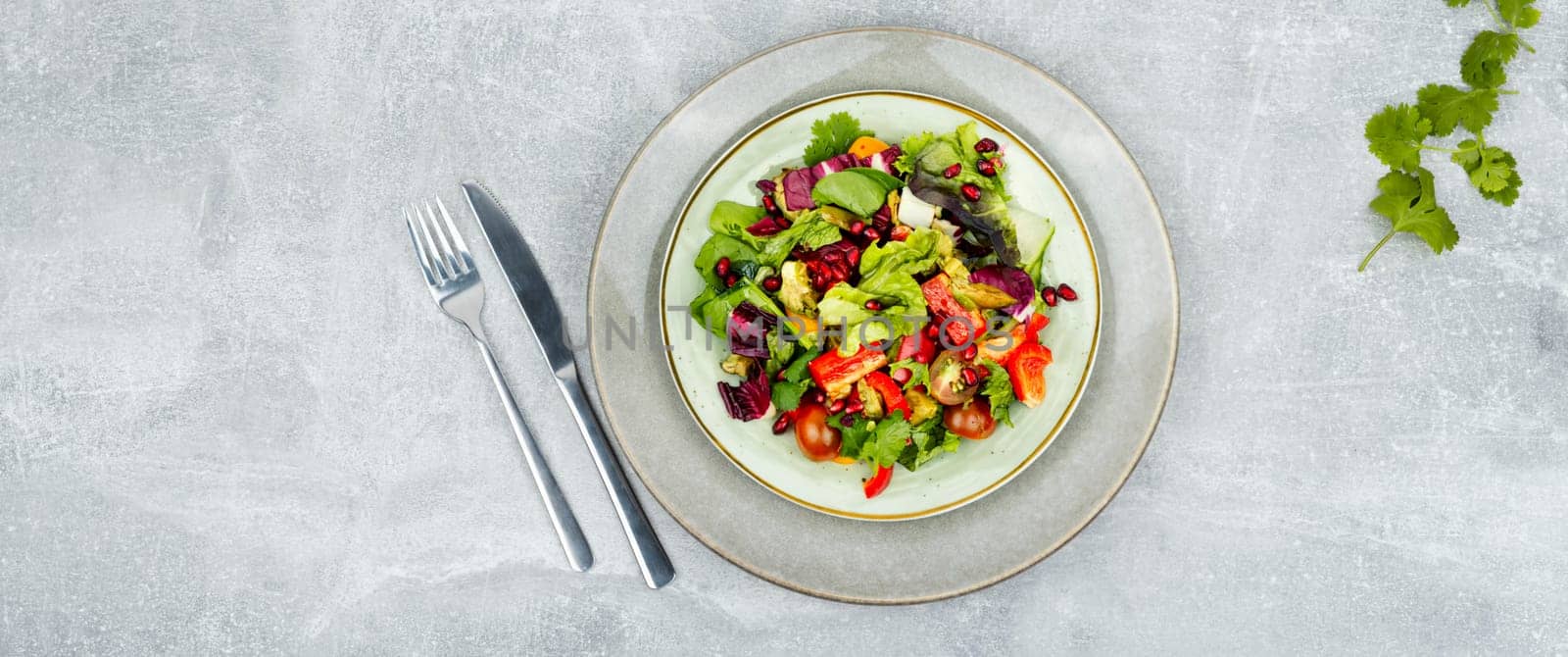 Vitamin salad with greens, pepper, red lettuce and cucumber, decorated with pomegranate.