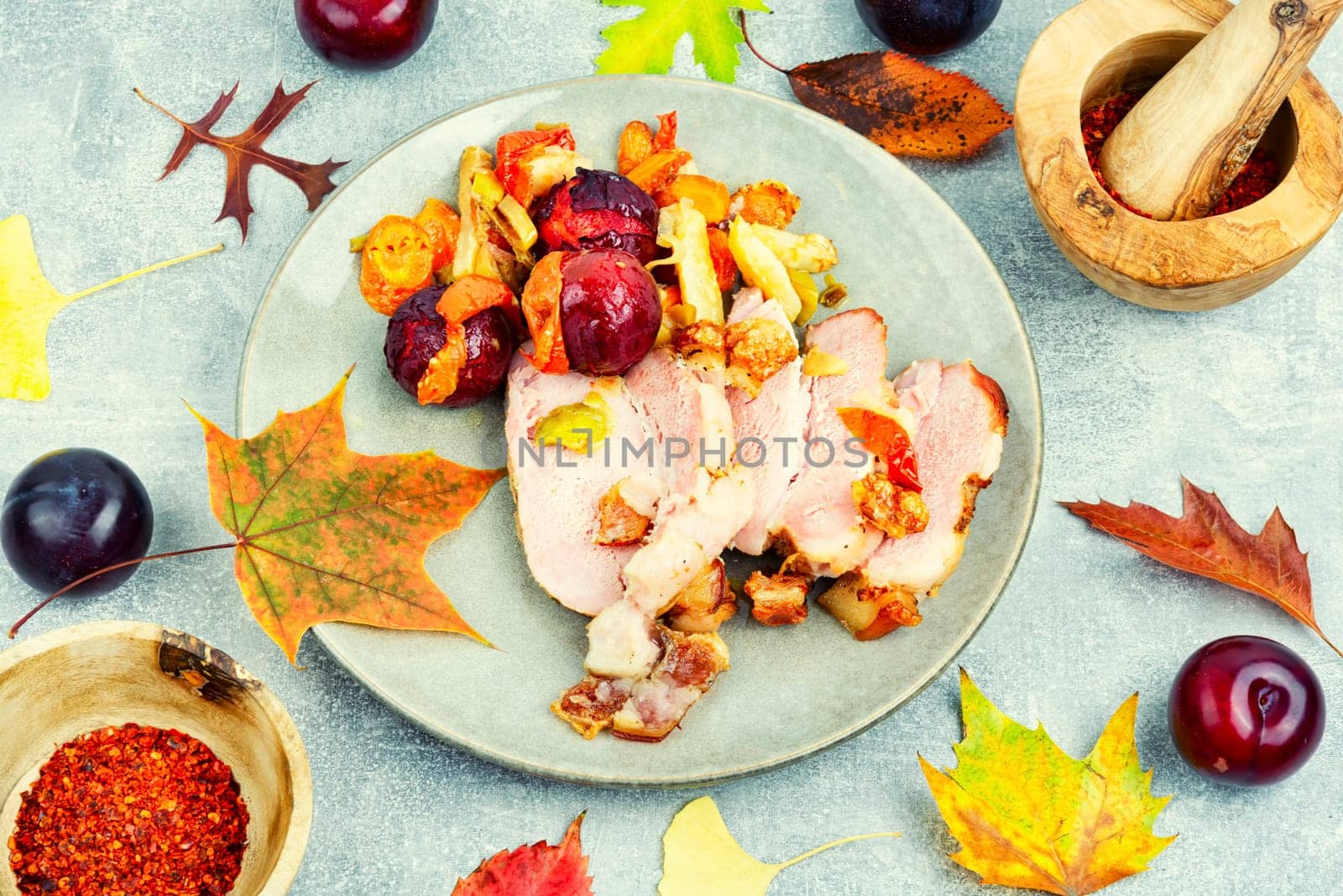 Piece of pork shoulder baked in the oven with vegetables and plums.