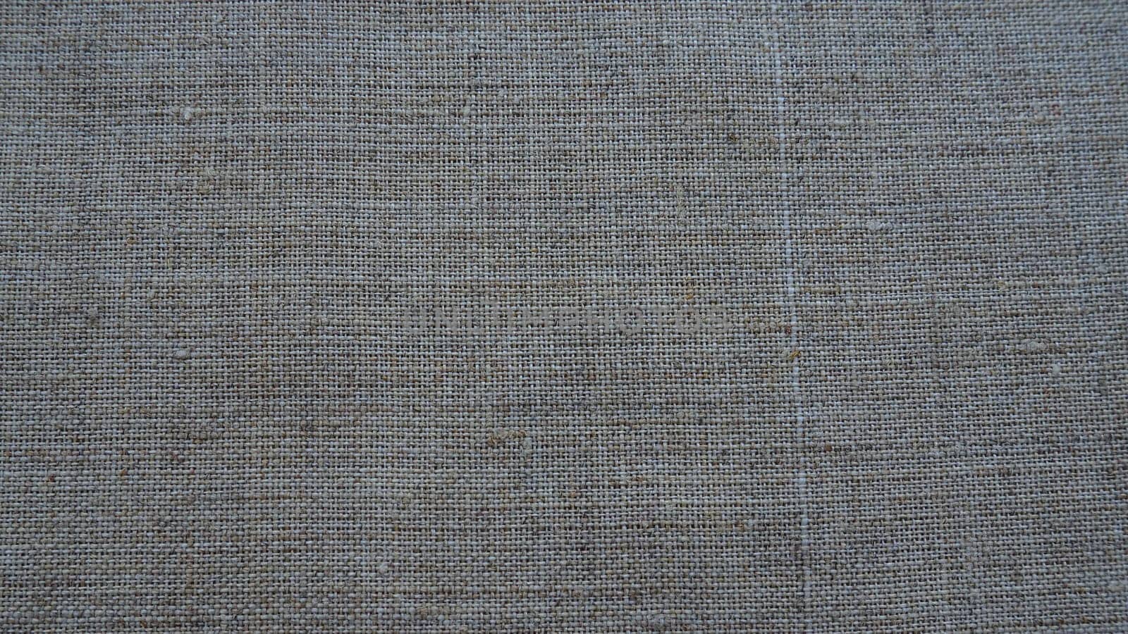 Fabric texture background. Gray fabric with weave. Natural slightly wrinkled look of the material. Uniform copy space background. Cotton, canvas or woolen thin fabric laid evenly on the surface