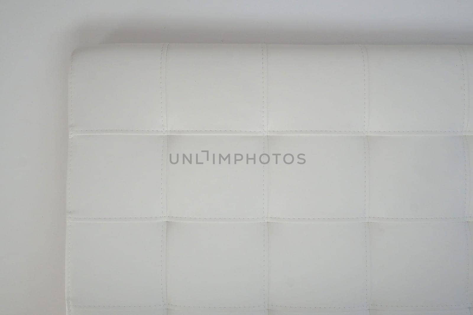 Soft headboard. Upholstery for furniture made of genuine or artificial leather and fabric. Soft headboard against a light wall