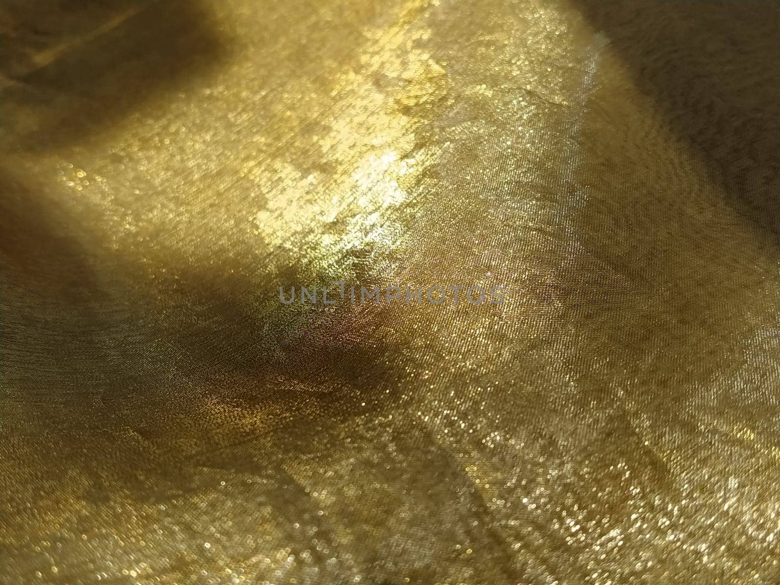 Curtain loops. Beautiful gold fabric. Organza in yellow, orange, beige and brown shades. Pleats in the fabric. Shiny gradient under the light. Folded silky tulle. Transparent curtain material.