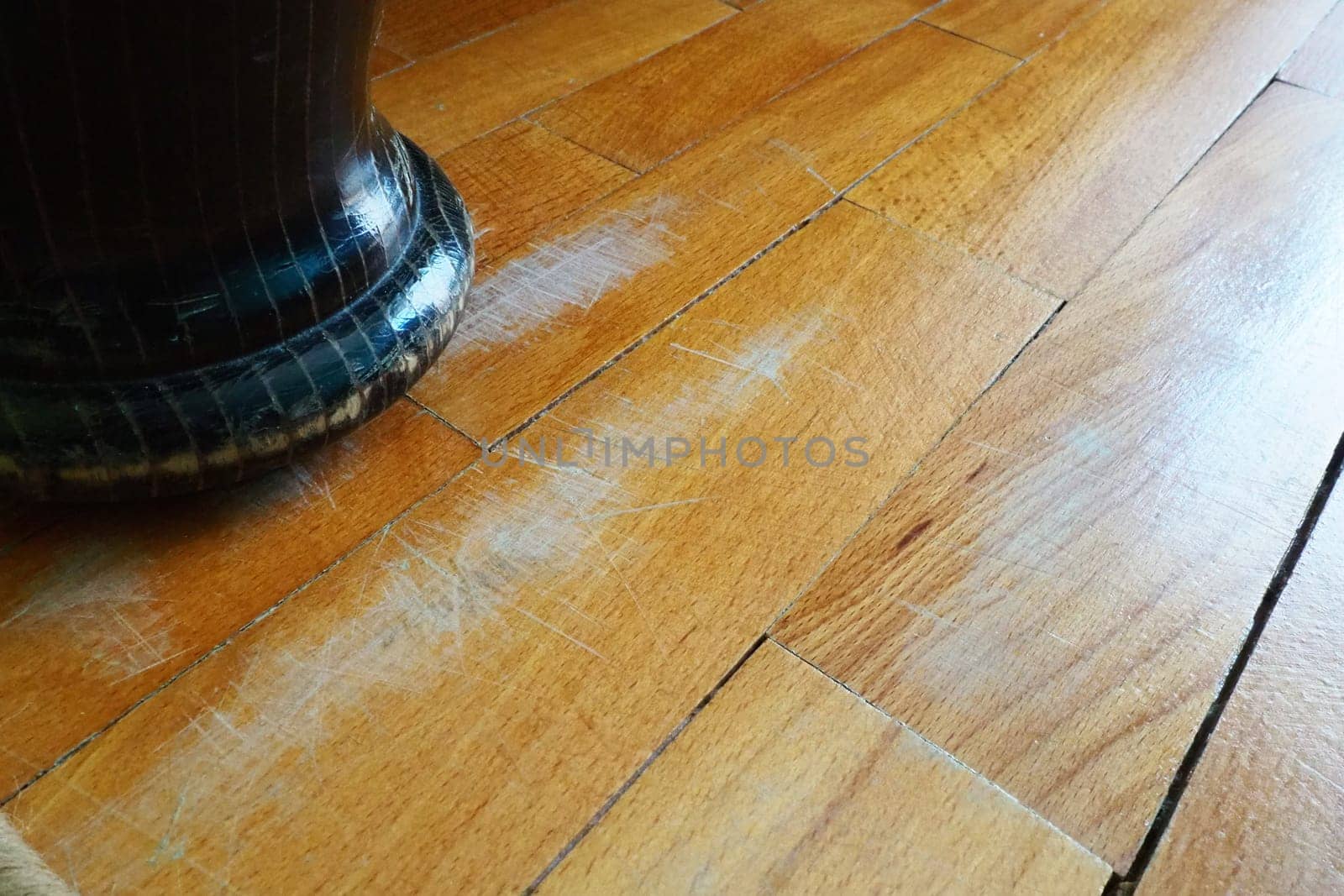 Scratched old parquet flooring needs maintenance. The parquet is damaged by scratches from prolonged use. The leg of an antique wooden bed scratched the floor.