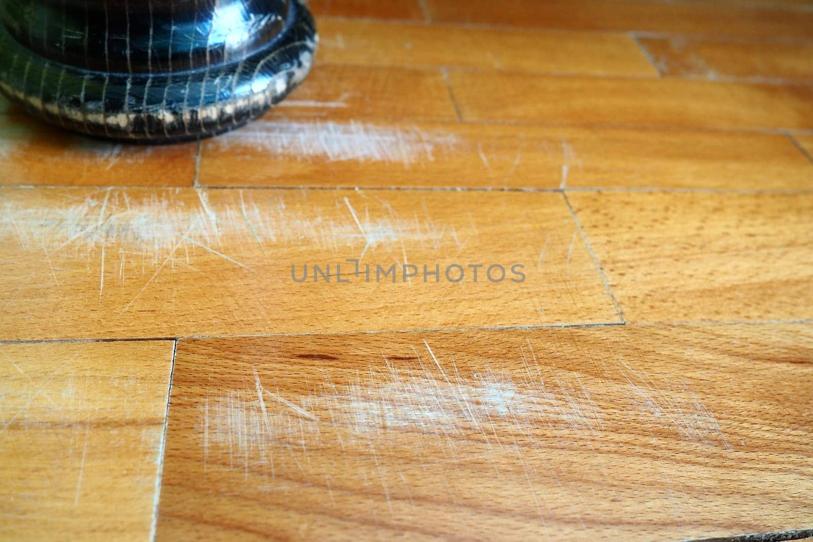 Scratched old parquet flooring needs maintenance. The parquet is damaged by scratches from prolonged use. The leg of an antique wooden bed scratched the floor.
