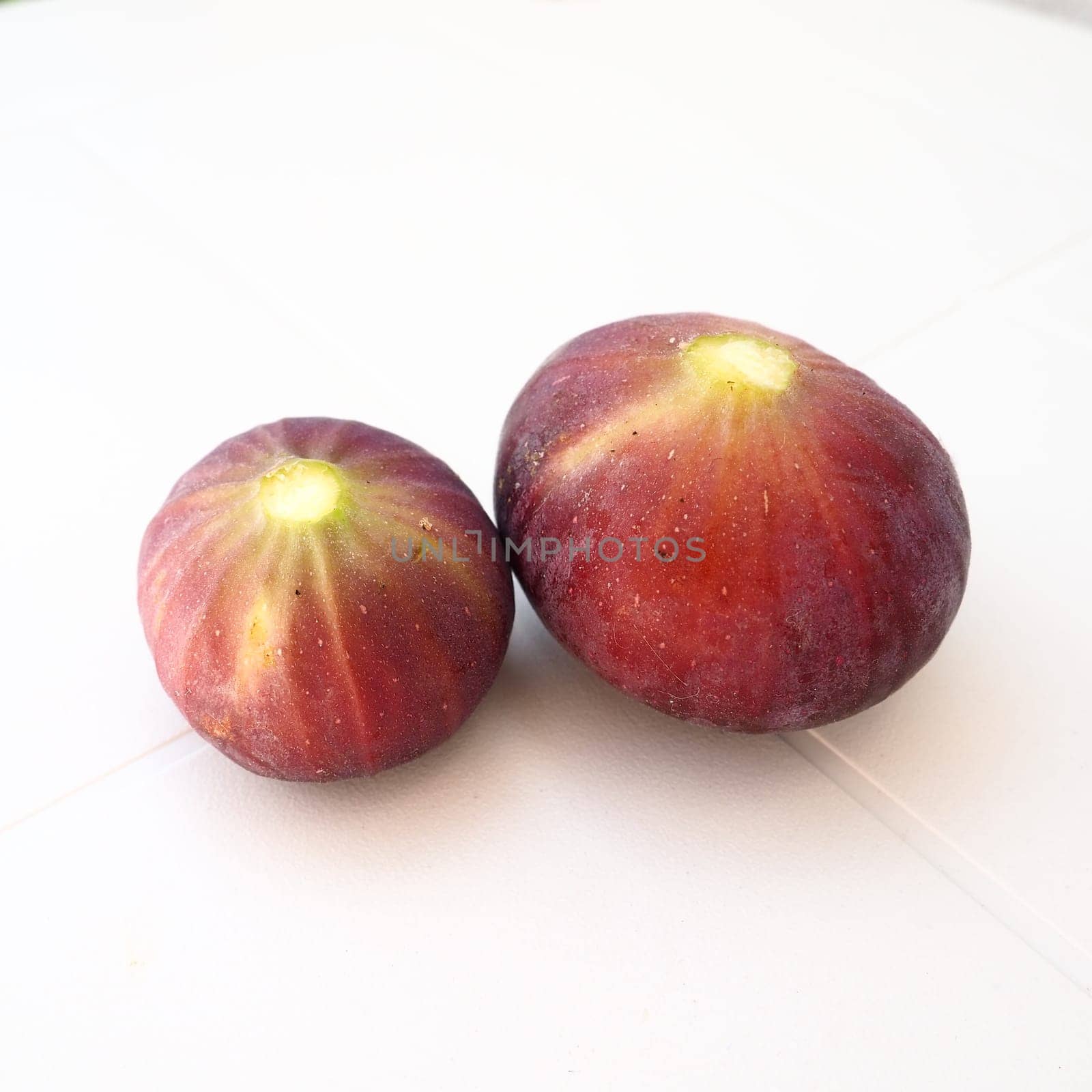 Fig or fig tree, or common fig tree, or Ficus carica is a subtropical deciduous plant of the genus Ficus of the Mulberry family. Ripe purple fig fruits on a light background. Healthy food.