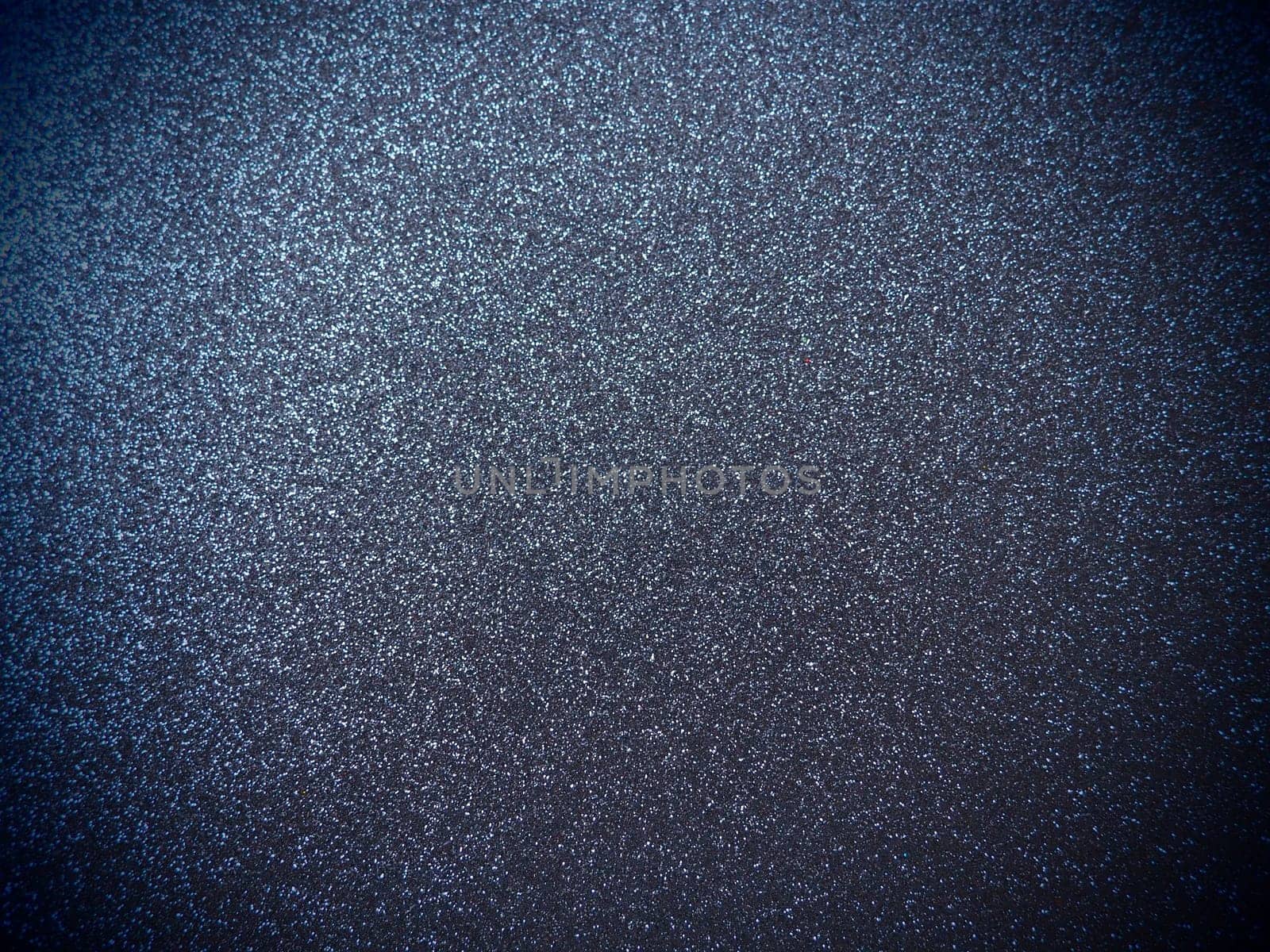 Deep blue shiny bokeh abstract background. Blue - black paper with sparkles. Festive backdrop with dark vignette.
