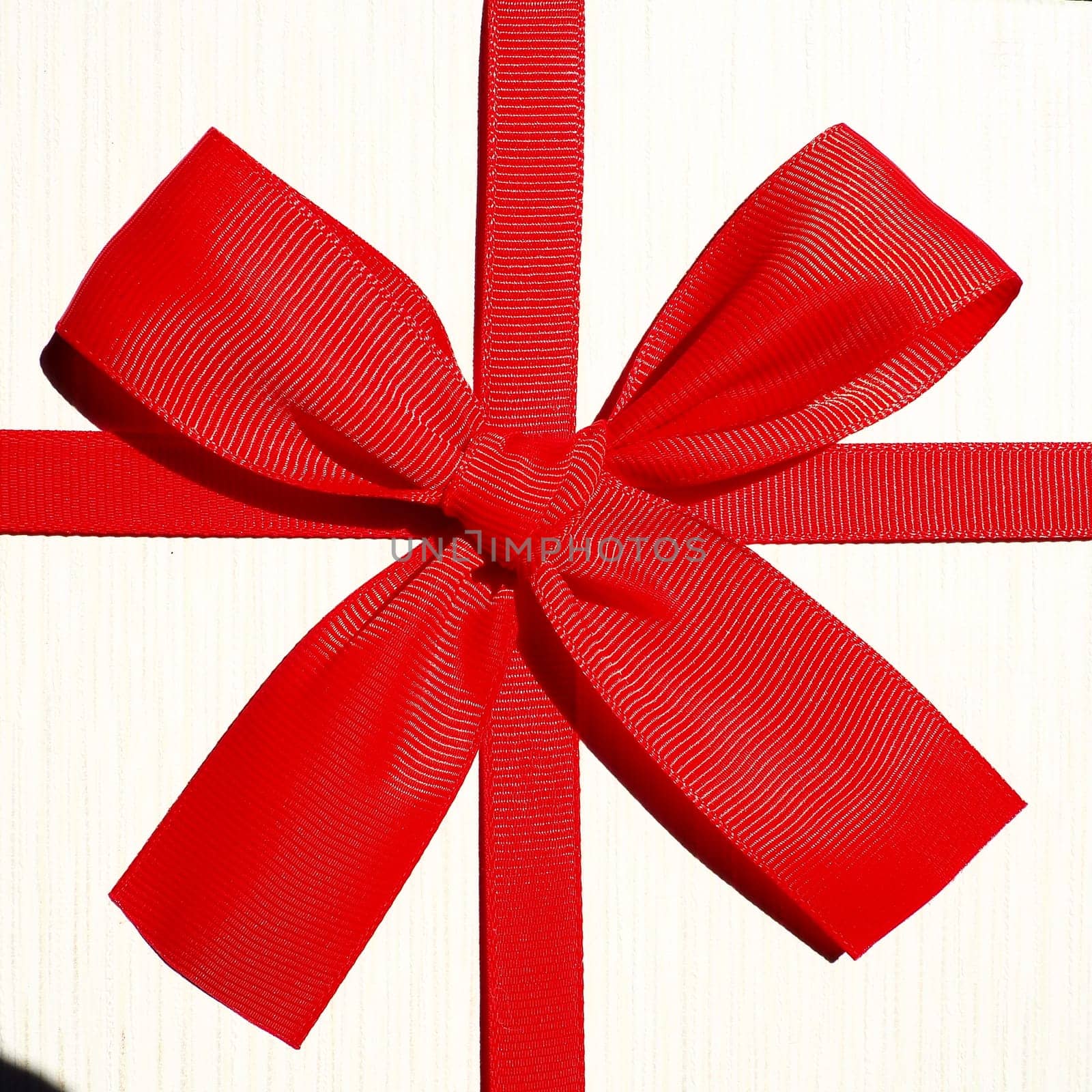 White gift box with red ribbon bow isolated on white background.