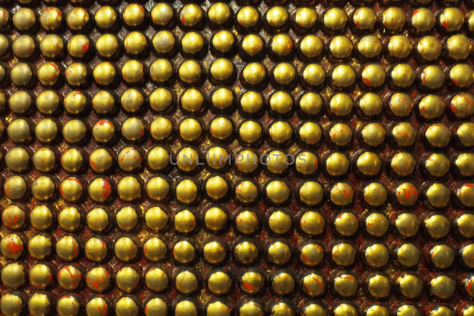 Pimples or spikes made of black and gold metal. Metal large rounded bulges are located geometrically. Unusual industrial abstract chain mail background