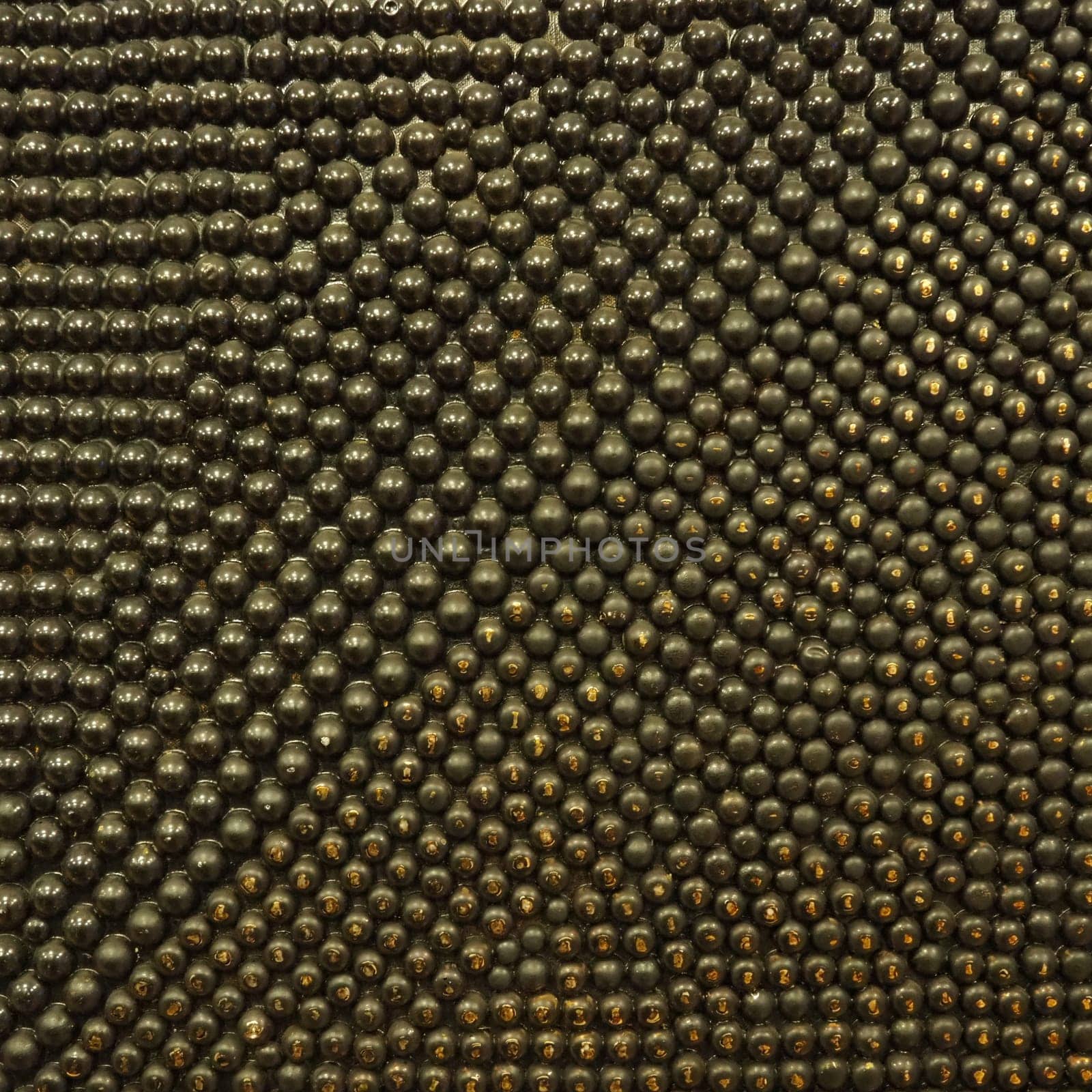 Pimples or spikes made of black and gold metal. Metal rounded bulges are located randomly. Unusual abstract background