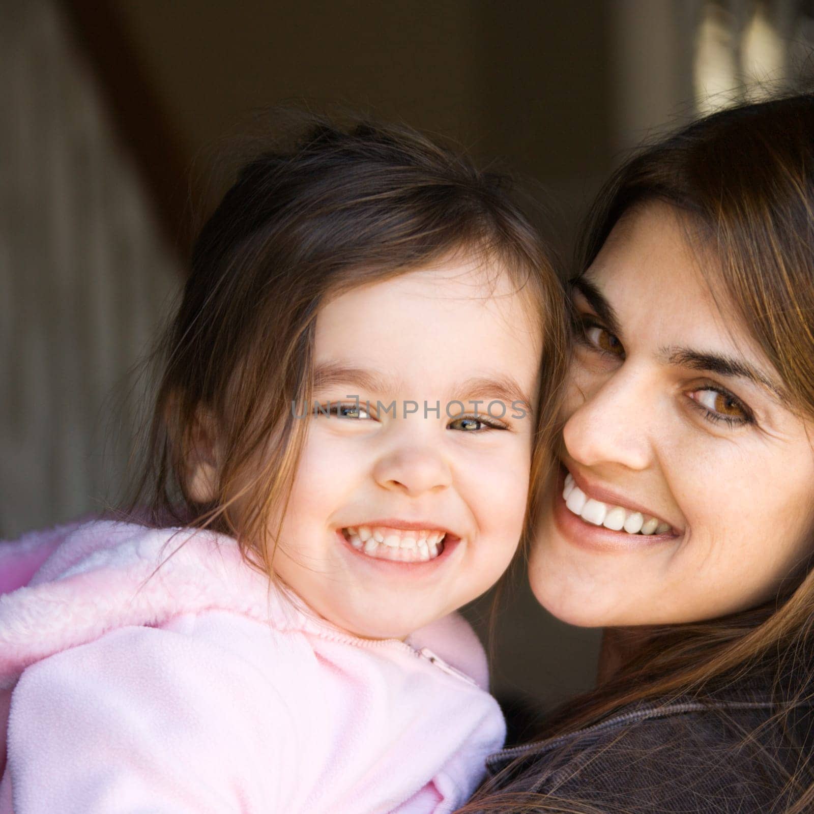 Caucasian mother holding daughter and smiling.