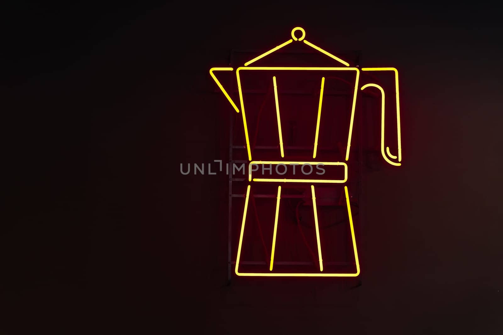 Yellow neon signage in the form of a Moka coffee maker against a black wall