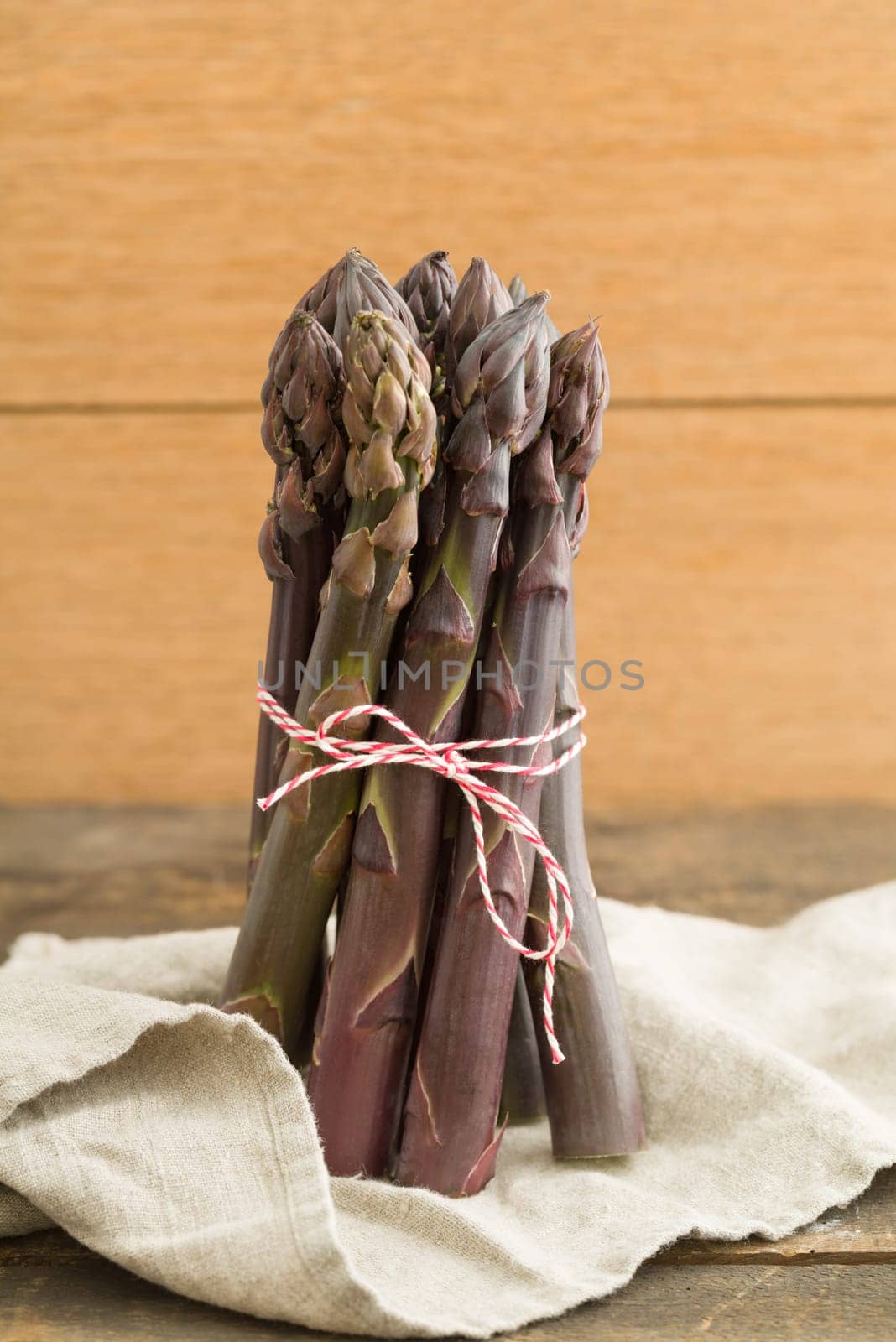 Bunch of violet asparagus on wooden table with linen cloth