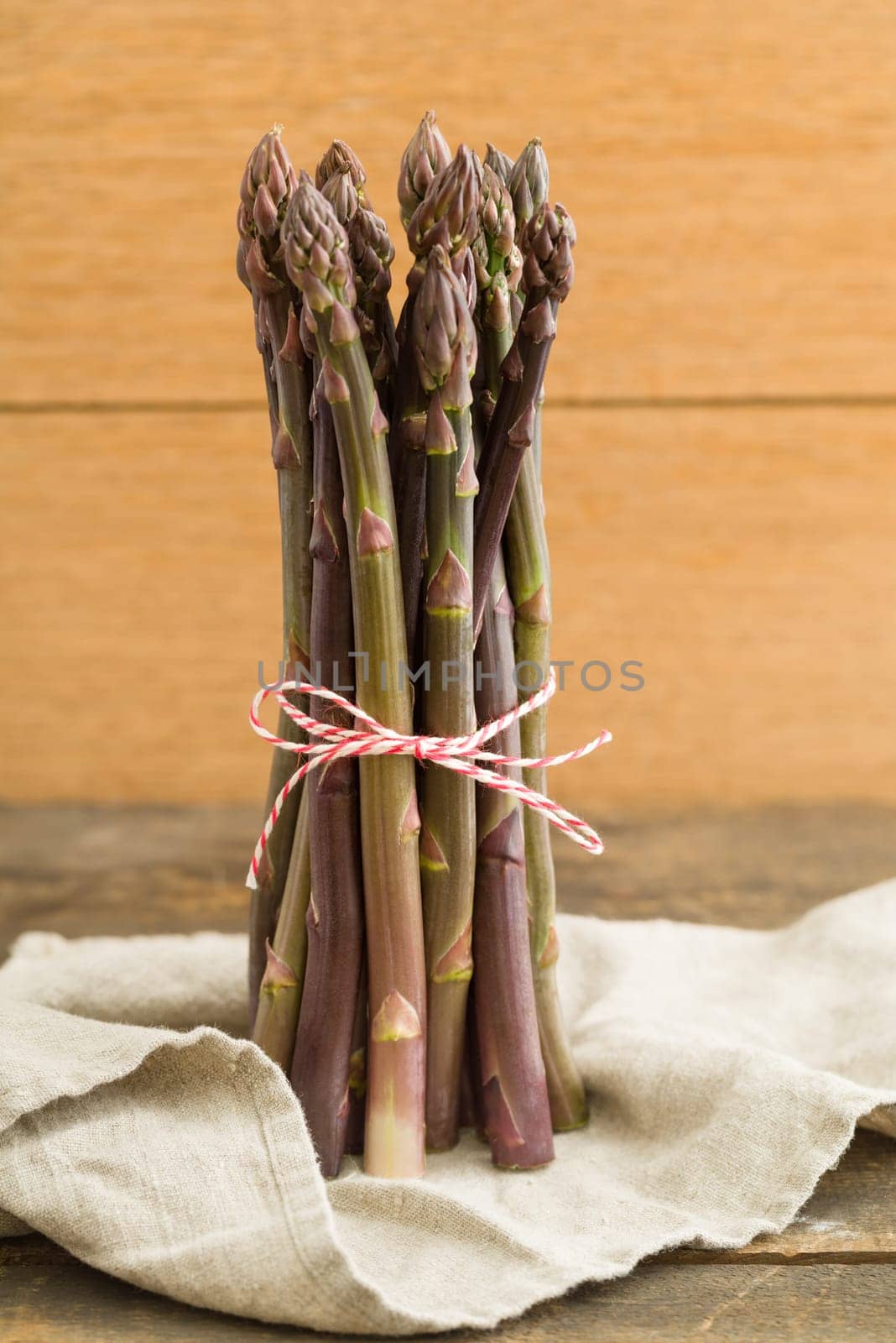 Bunch of violet asparagus on wooden table with linen cloth