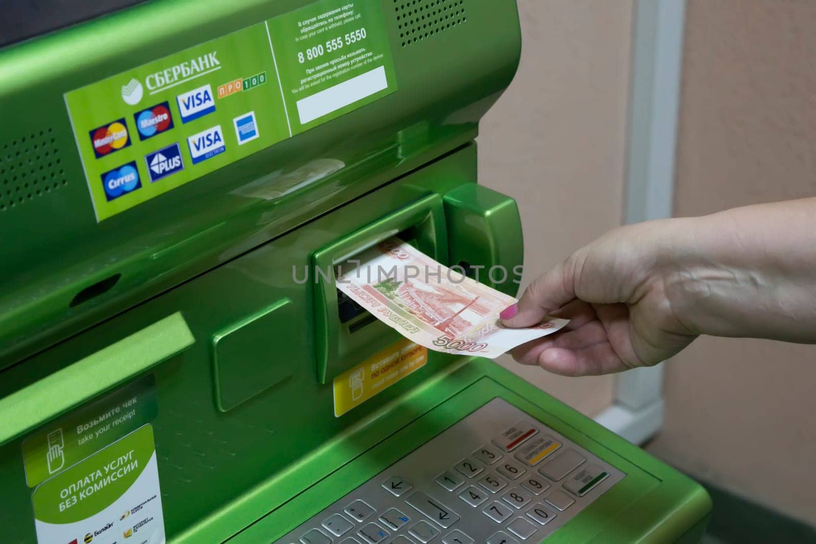The hand of man (woman) insert a banknotes into a slot of the Sberbank ATM.