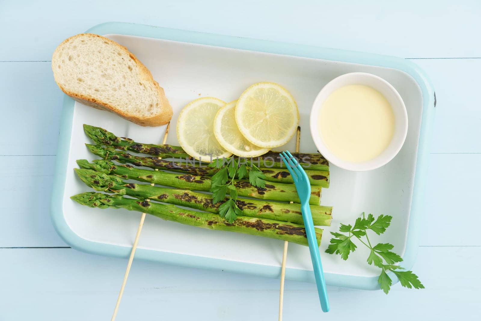 Grilled green asparagus skewers with Hollandaise sauce,baguette and lemon