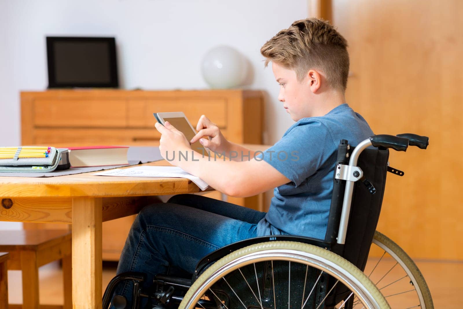 disabled boy in wheelchair doing homework and chatting in the internet