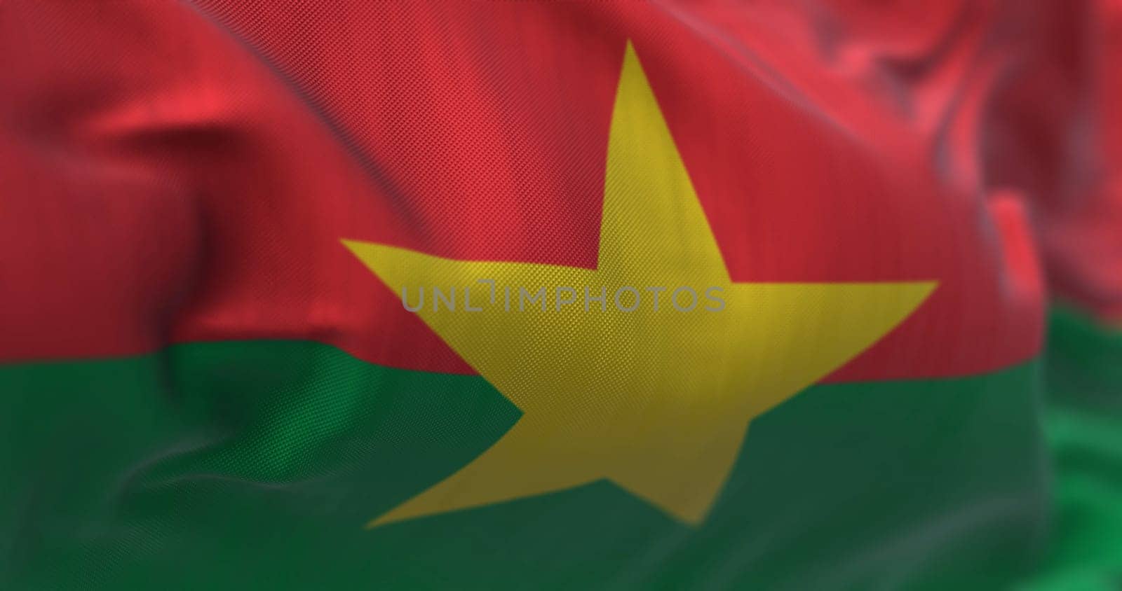 Close-up view of the Burkina Faso national flag waving in the wind. Burkina Faso is a country in West Africa. Fabric textured background. Selective focus. Realistic 3d illustration