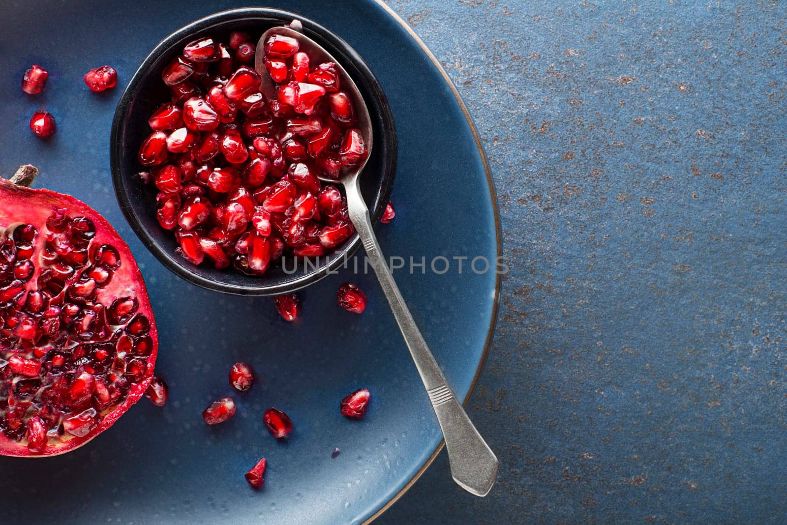 Healthy ripe pomegranate fruit opened and split with seeds on white plate