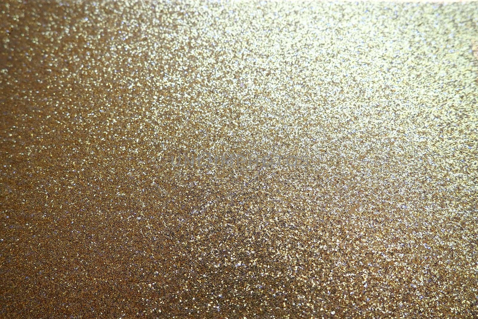 Gold close up. Golden glitter texture background. Sparkling glitter wrapping paper with sequins and sparkles. Festive golden bokeh and glitter. Beautiful background. Bokeh light of gold glitters.