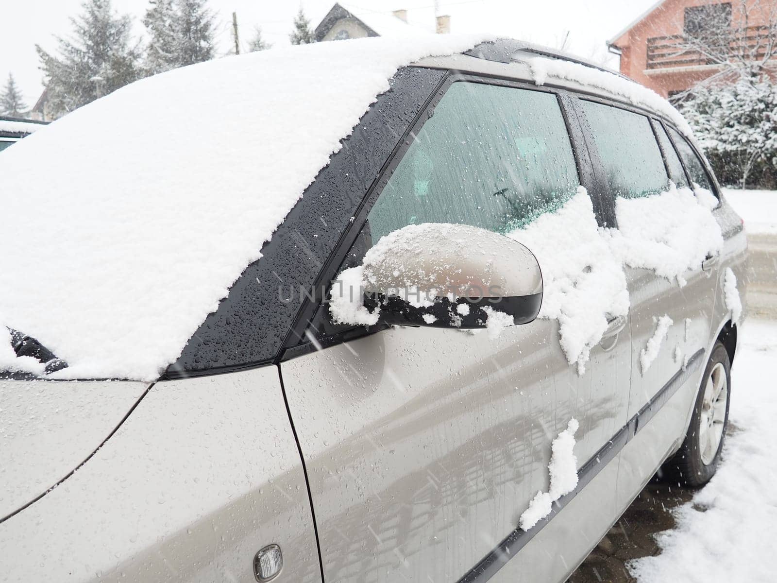 Snow and ice on the windshield, retrovisors and rear-view mirrors of the car. Winter driving conditions. Snow cleaning. Road traffic in winter. Metallic car. Snowdrifts and slush