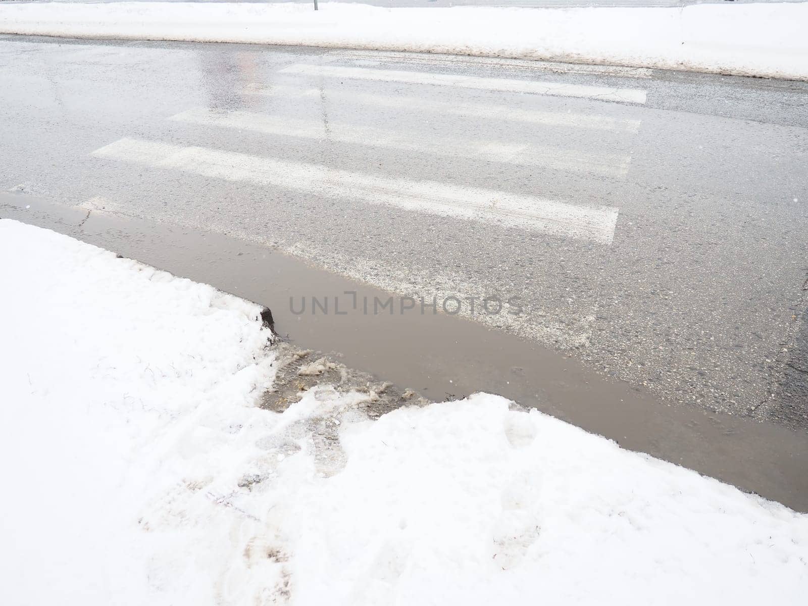 Snow, ice, slush and winter mud at a pedestrian crossing. The air temperature is about 0. Difficult driving conditions. Braking distance of the car. Traffic Laws. Infrastructure and road services.