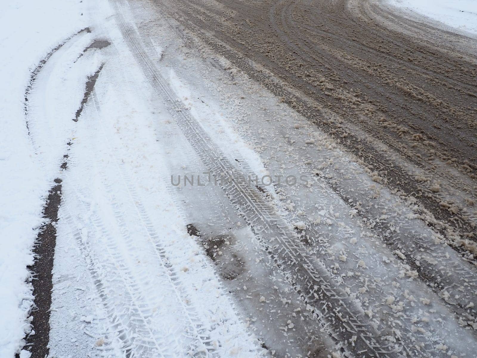 A fork or siding from a roundabout. Snowdrifts on the side of the road. Bad weather and traffic. Snow on asphalt. Difficult driving conditions. Winter slosh on the road. Braking distance of a car.