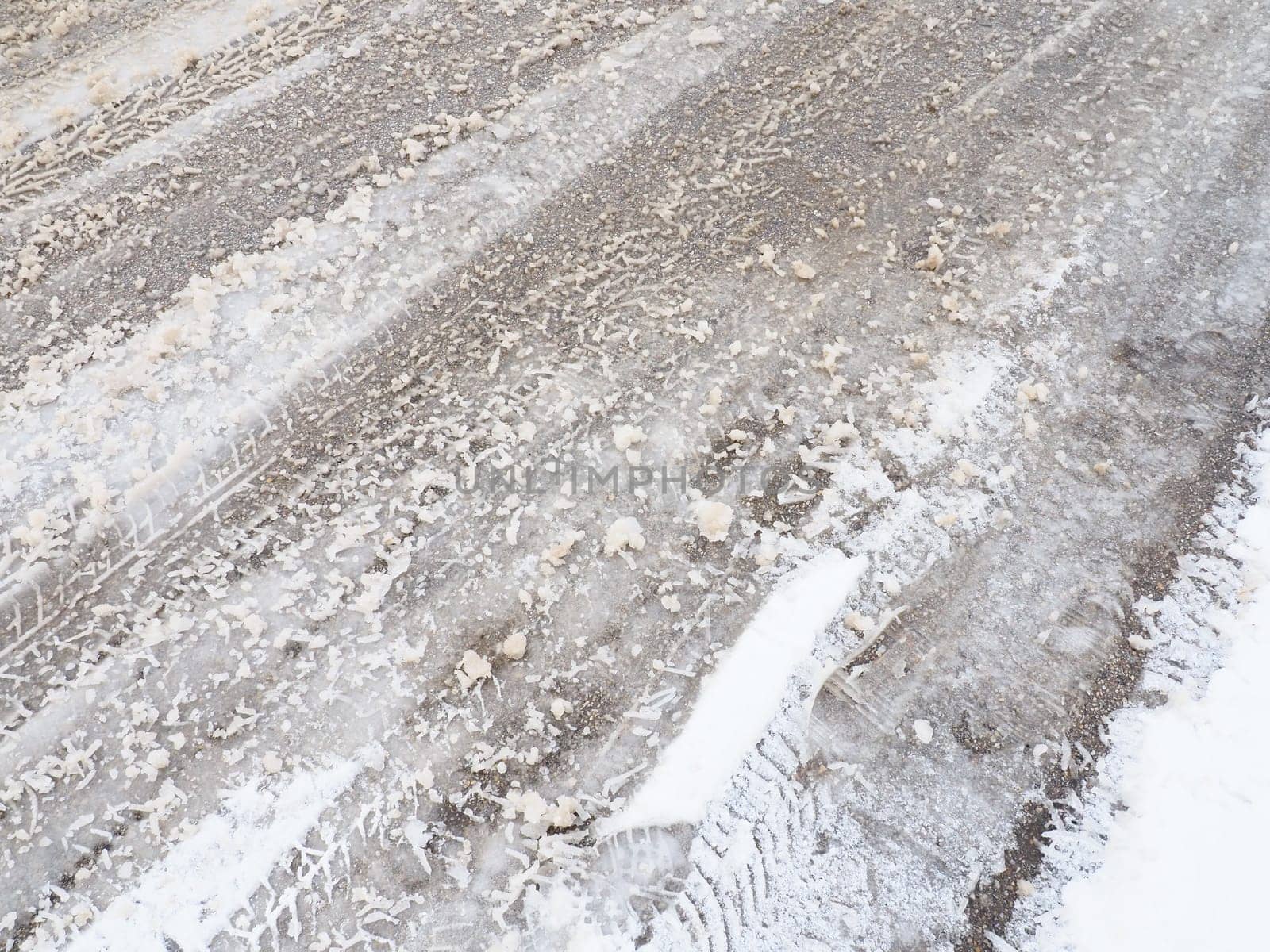 Snowdrifts on the side of the road. Bad weather and traffic. Snow on asphalt. Difficult driving conditions. Winter slosh on the road. Braking distance of a car