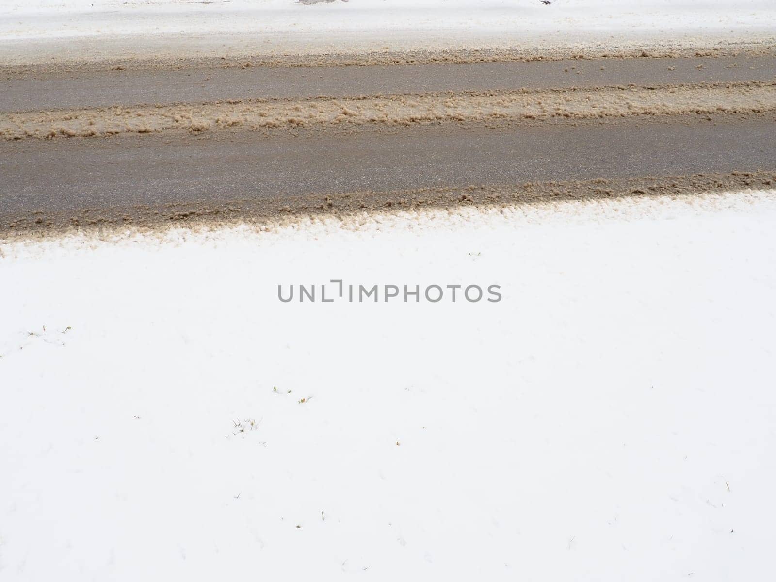 Snowdrifts on the side of the road. Bad weather and traffic. Snow on asphalt. Difficult driving conditions. Winter slosh on the road. Braking distance of a car