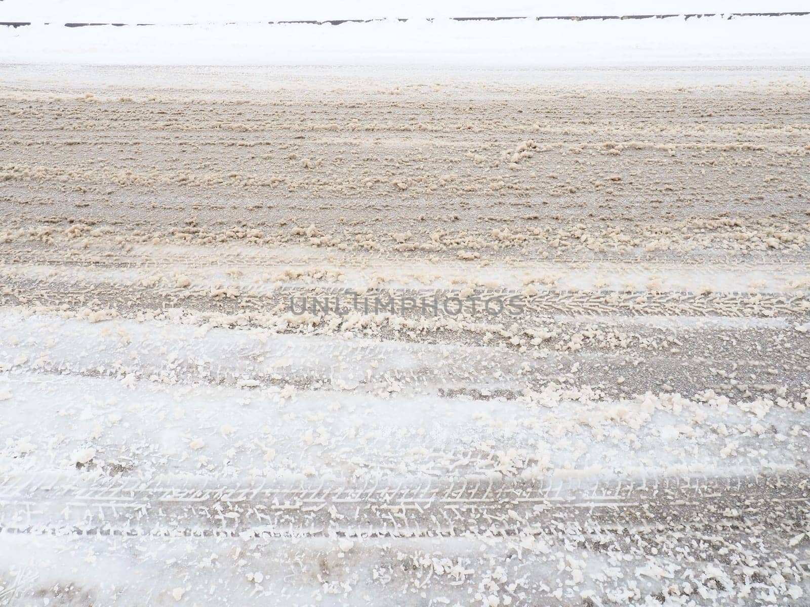 Snowdrifts on the side of the road. Bad weather and traffic. Snow on asphalt. Difficult driving conditions. Winter slosh on the road. Braking distance of a car