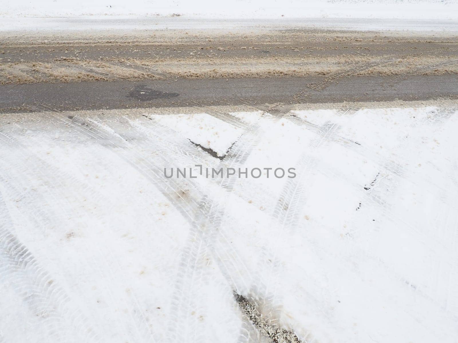 Snowdrifts on the side of the road. Bad weather and traffic. Snow on asphalt. Difficult driving conditions. Winter slosh on the road. Braking distance of a car