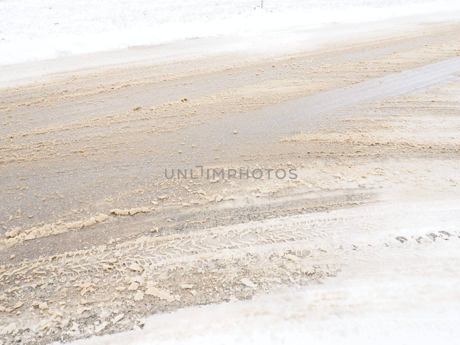 Snowdrifts on the side of the road. Bad weather and traffic. Snow on asphalt. Difficult driving conditions. Winter slosh on the road. Braking distance of a car