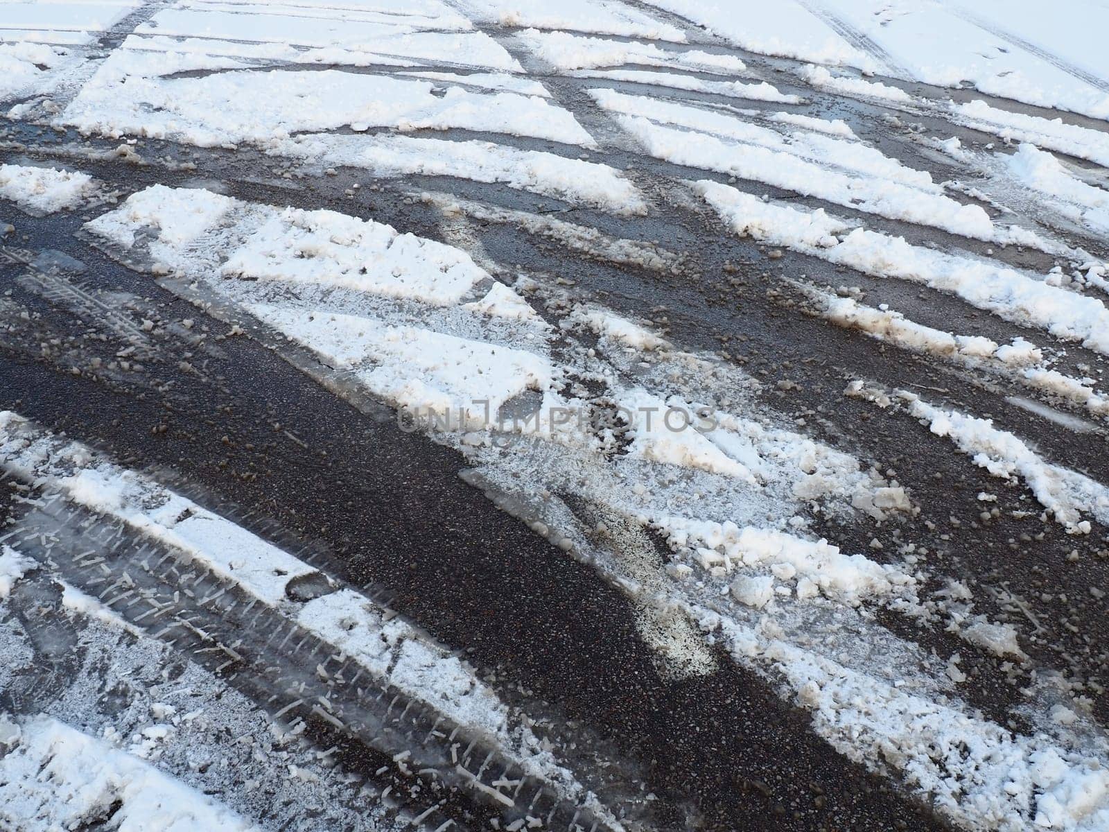 A fork or siding from a roundabout. Snowdrifts on the side of the road. Bad weather and traffic. Snow on asphalt. Difficult driving conditions. Winter slosh on the road. Braking distance of a car.