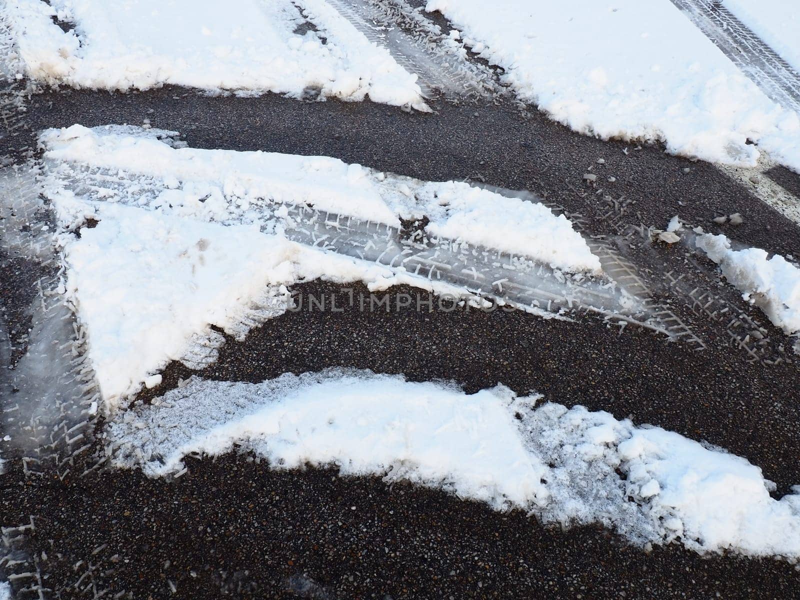 Snowdrifts on the side of the road. Bad weather and traffic. Snow on asphalt. Difficult driving conditions. Winter slosh on the road. Braking distance of a car
