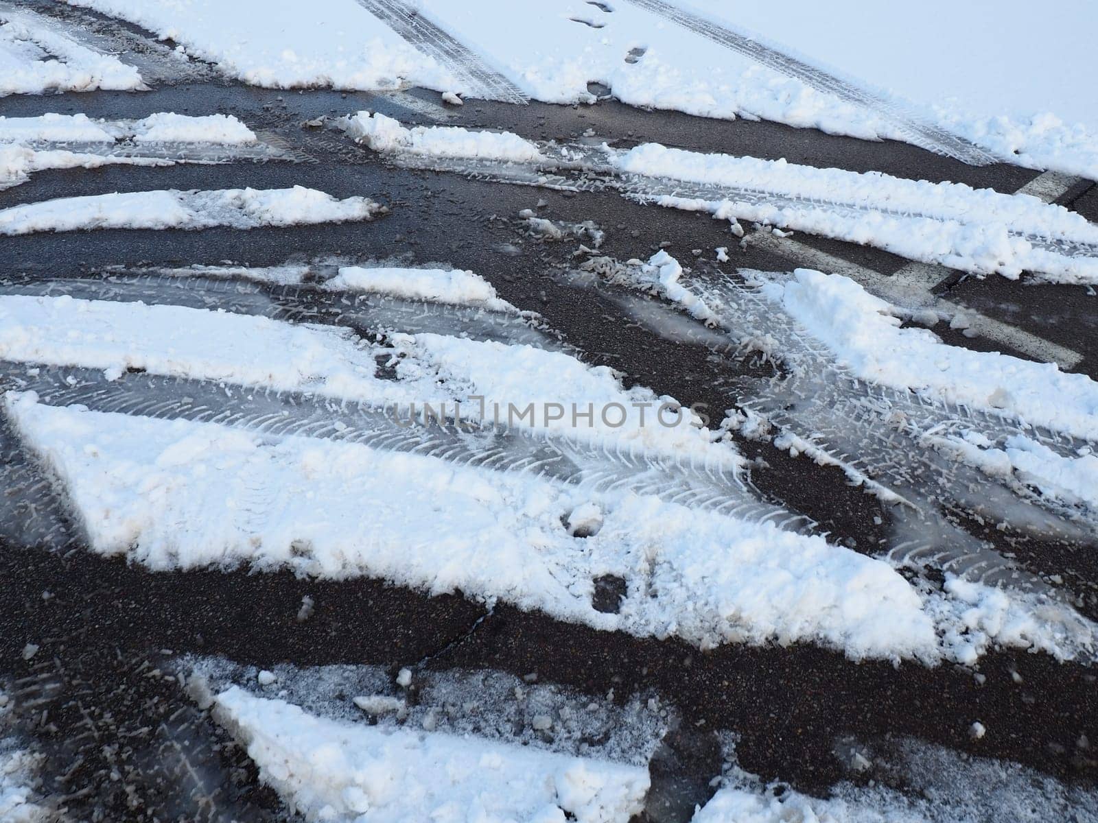 A fork or siding from a roundabout. Snowdrifts on the side of the road. Bad weather and traffic. Snow on asphalt. Difficult driving conditions. Winter slosh on the road. Braking distance of a car.