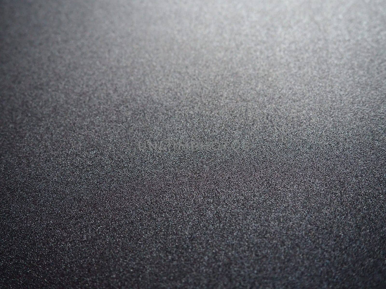 Black glitter texture christmas background. Bent shiny velvet paper.