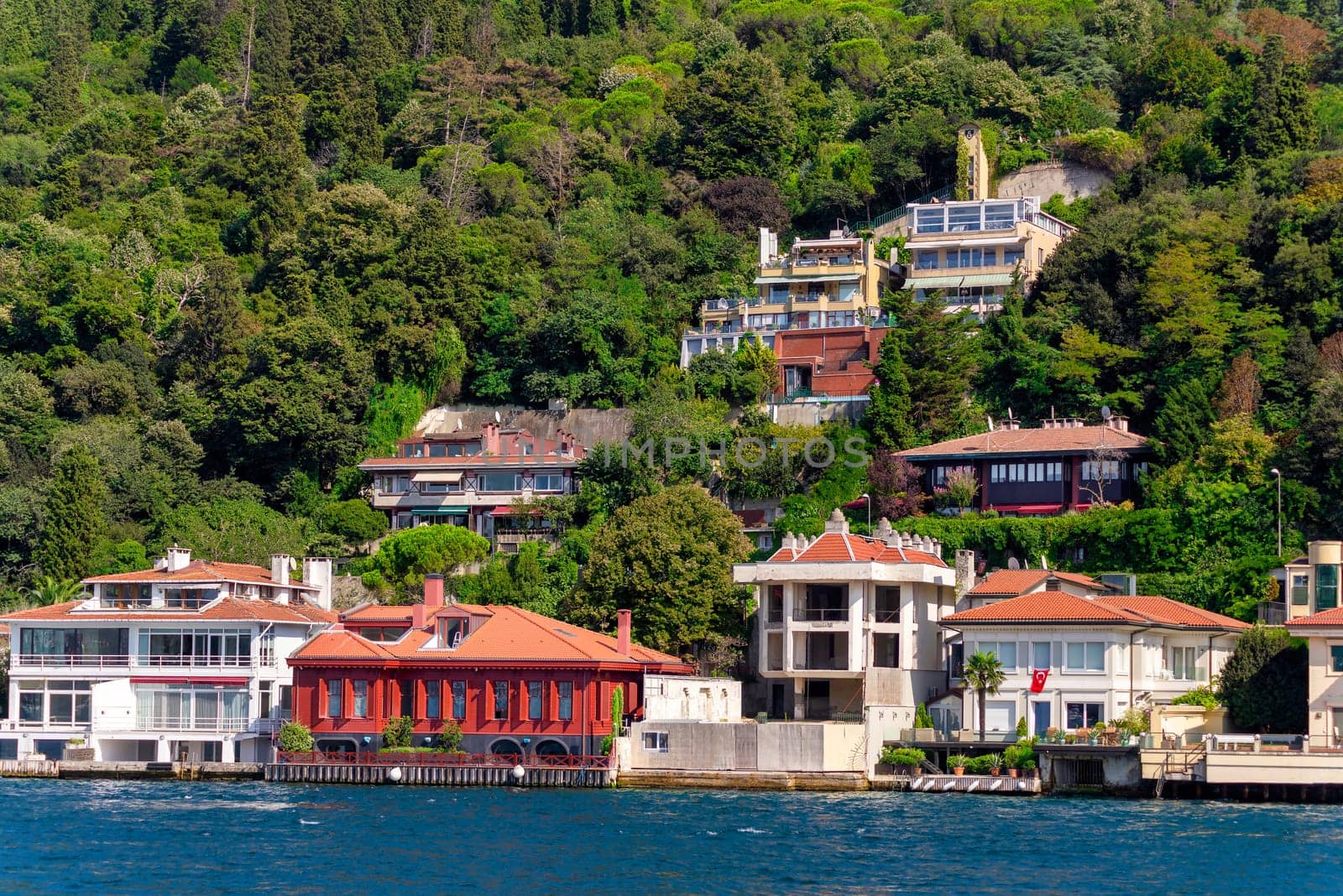 View from Bosphorus strait of the green mountains of the Asian side, with traditional houses and dense trees in a summer day, Istanbul, Turkey