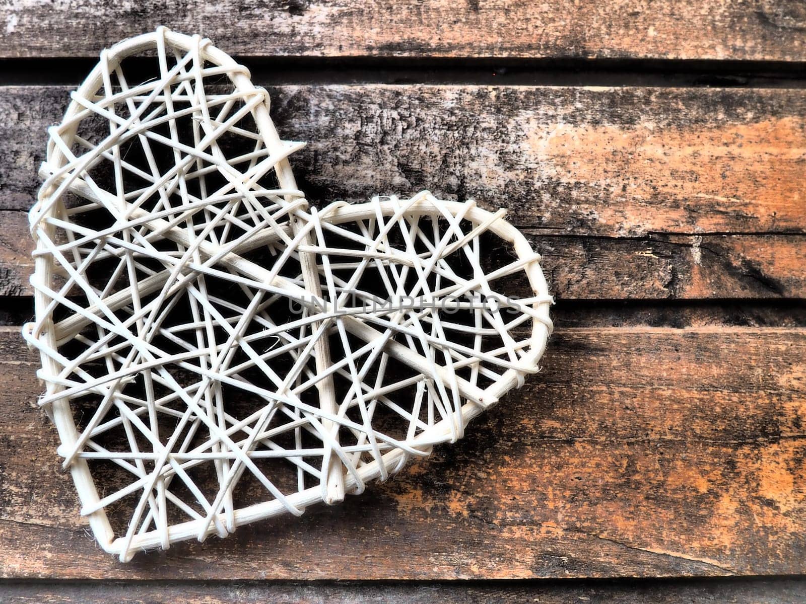 A heart woven from rustic light rods or threads. Wicker form handmade. Valentine's Day. Postcard. Wooden texture background. Love concept.