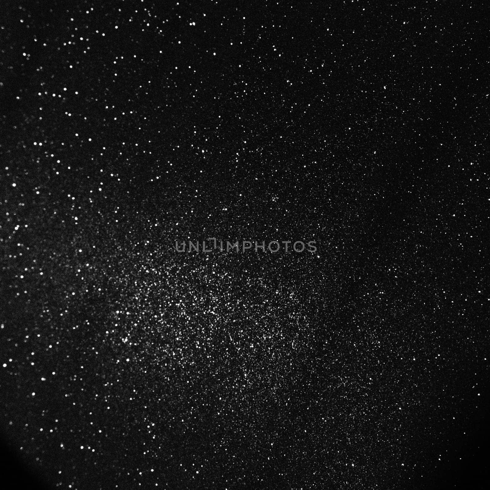 Black bokeh texture on black background. White glitter or illuminated dust.