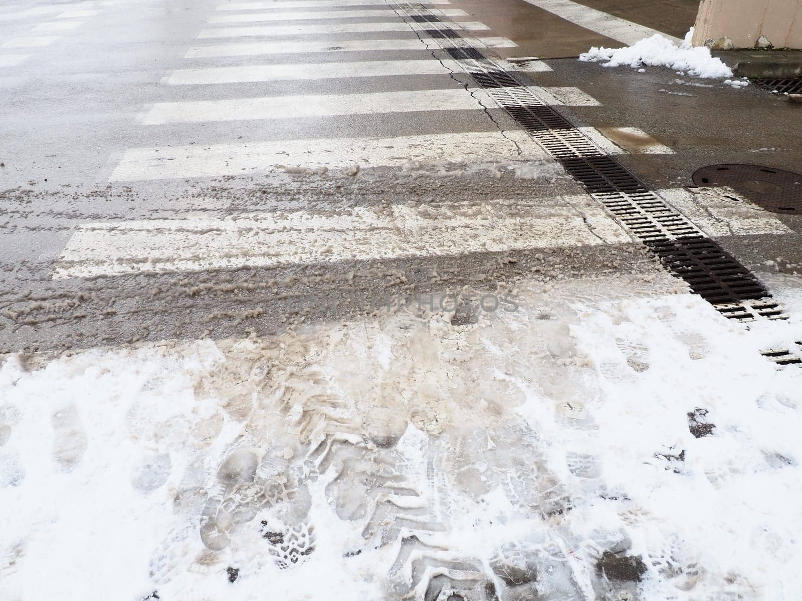 Snow, ice, slush and winter mud at a pedestrian crossing. The air temperature is about 0. Difficult driving conditions. Braking distance of the car. Traffic Laws. Infrastructure and road services.