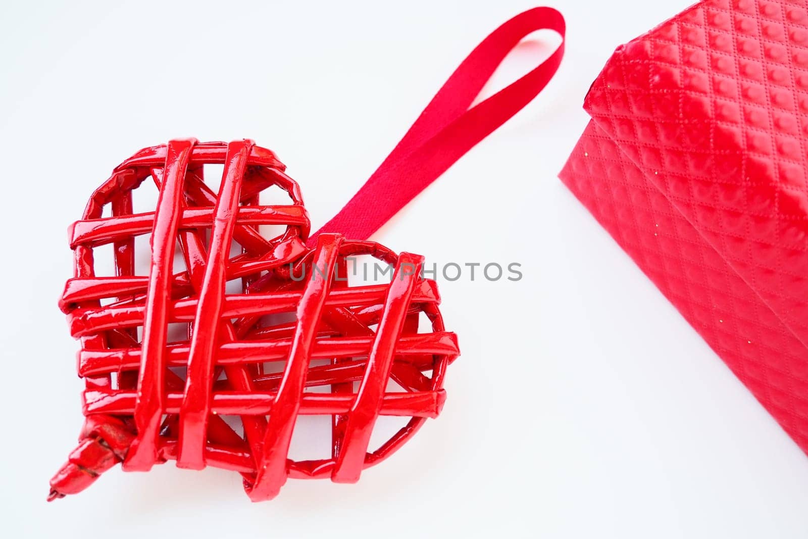 Red braided heart with a silk ribbon on a white background. Valentine's Day. Red gift box. copyspace. Flat lay.