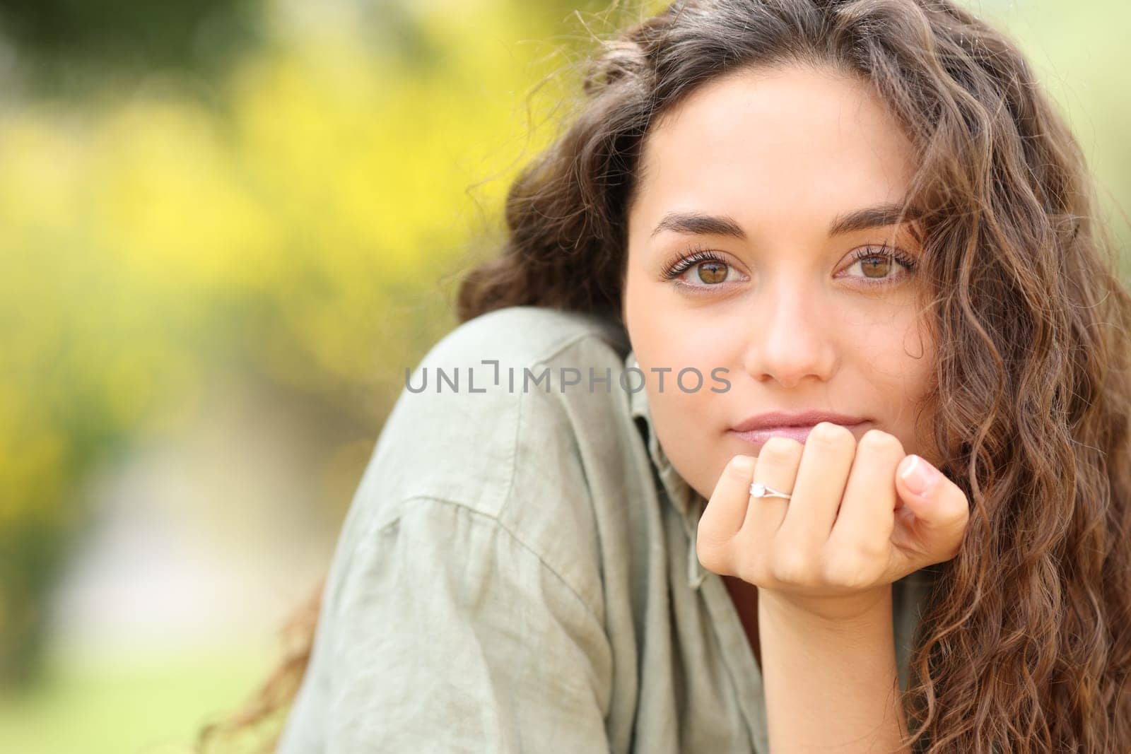 Portrait of a woman looking at you with engagement ring in a park