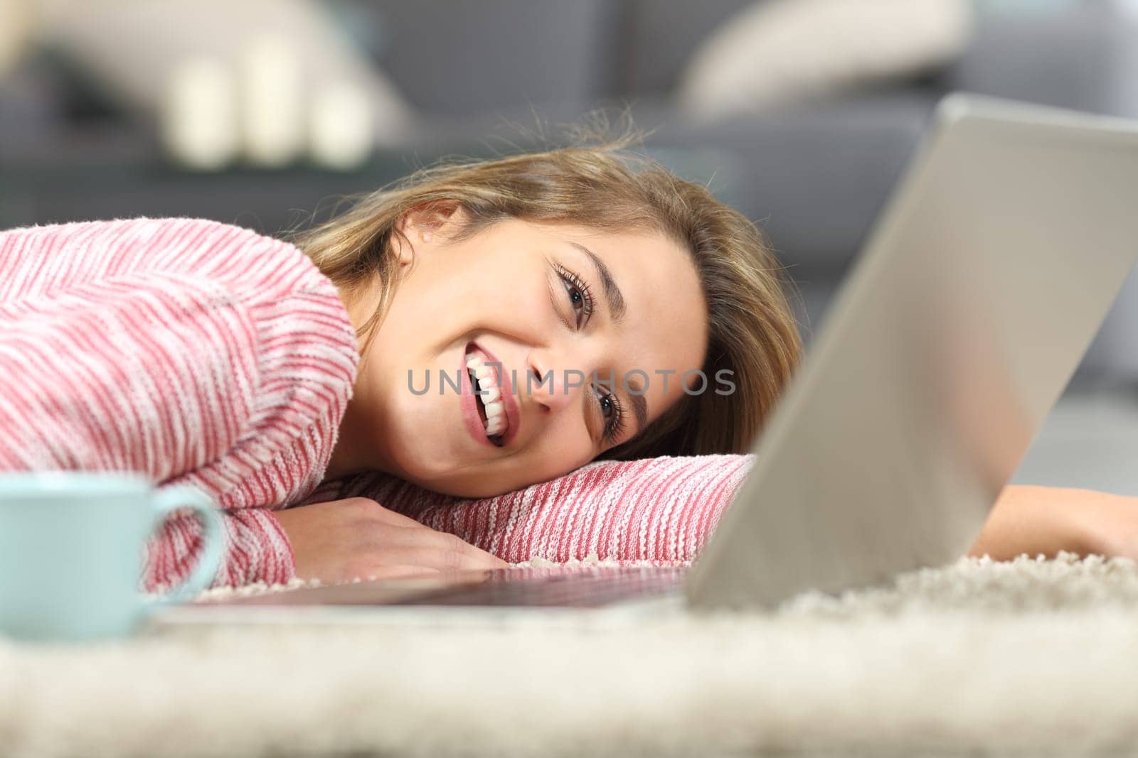 Happy woman laughing checking laptop on the floor at home