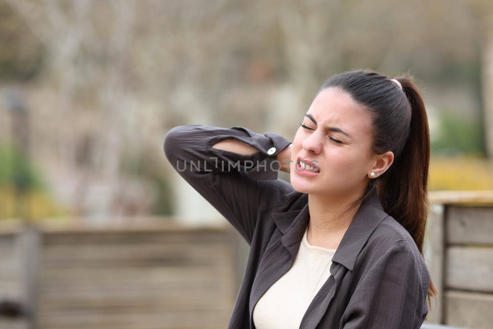 Teen complaining in a park suffering neck ache