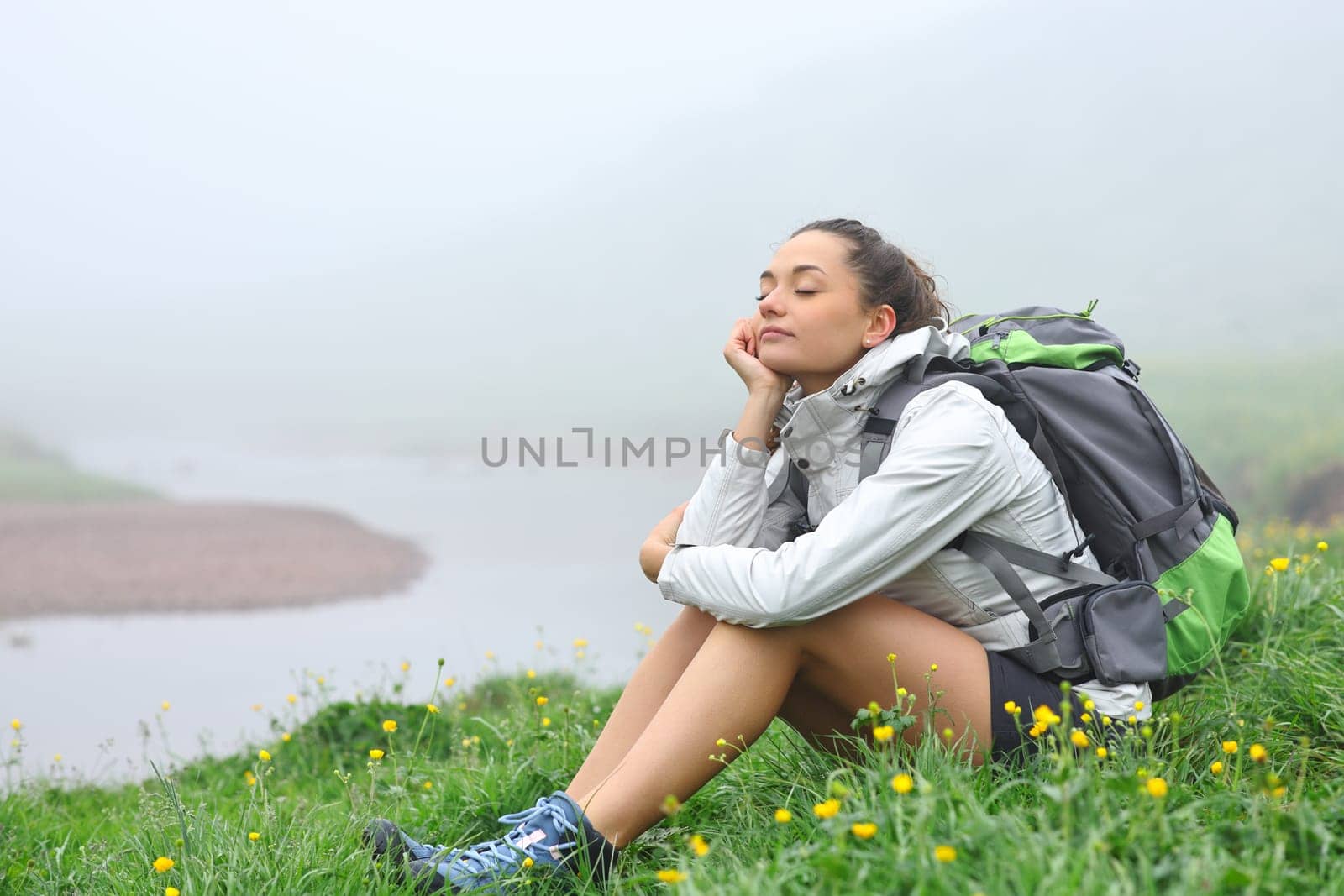 Hiker resting in a foggy day sitting in the mountain