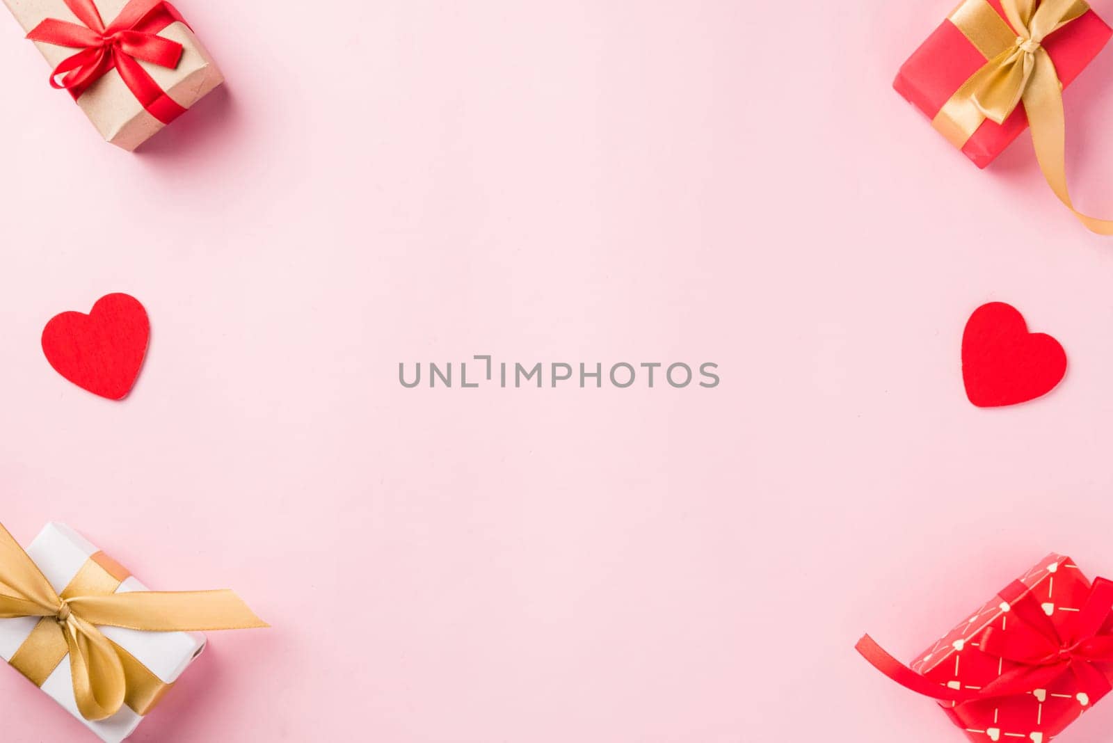 Valentines' day background. Frame made of red gift box with ribbon bow and wood red hearts shaped composition greeting card for love isolated on pink background with copy space. Top View from above