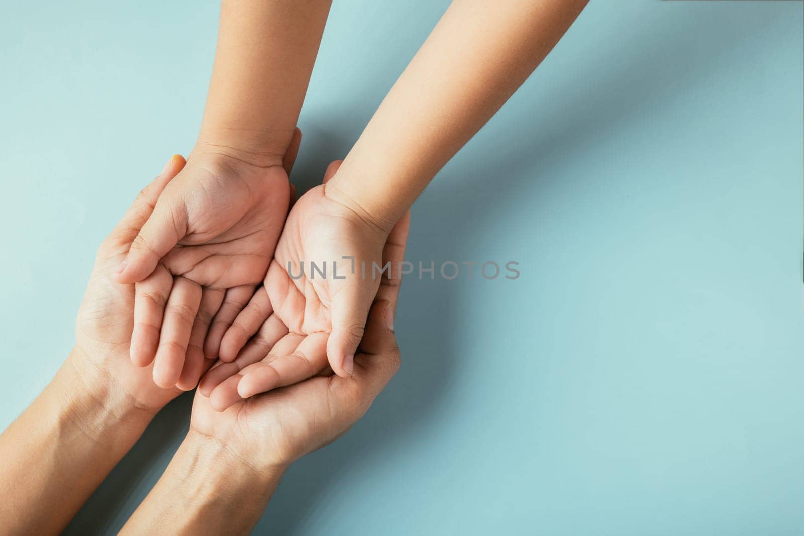 Closeup top view family hands stack palms studio shot isolated on blue background, parents and kid holding empty free space on hand together, Gesture sign of support and love, Family and parents day