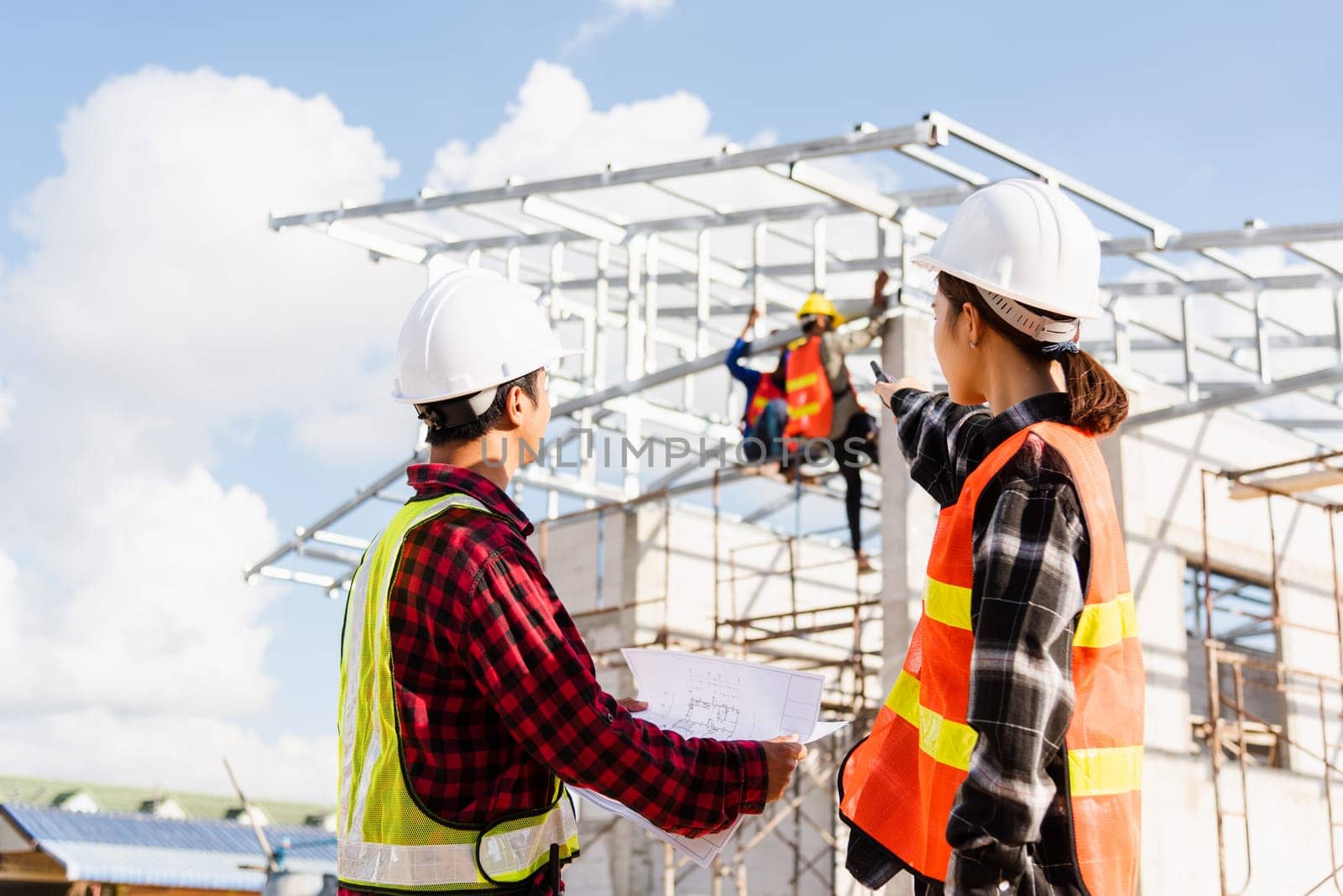 Back two architect and client discussing help create plan with blueprint home building at construction site. Asian engineer foreman worker man and woman meeting talking on drawing paper project