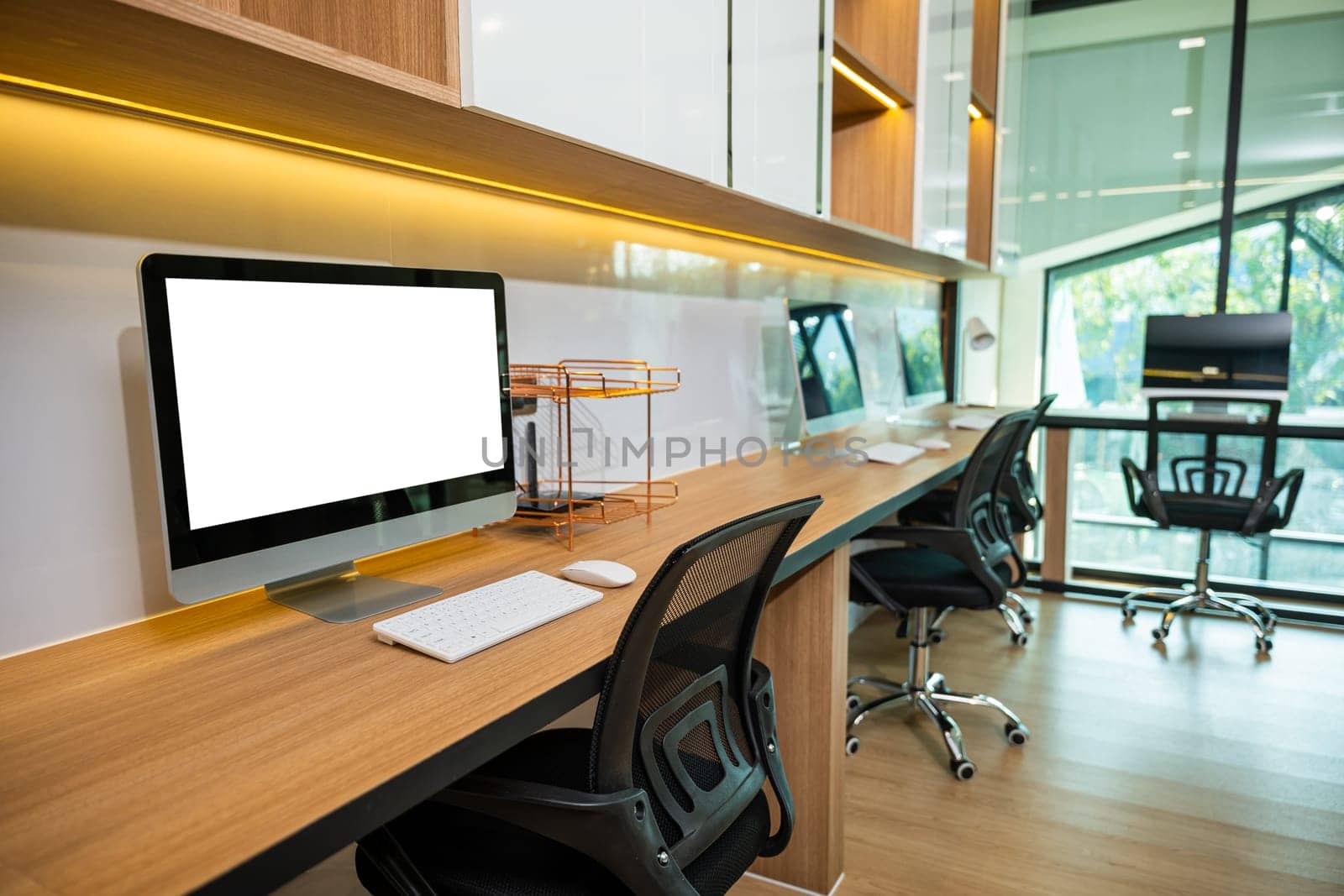 Workspace desk. Computer desktop blank screen in front of window in office, blank screen monitor on modern working desk, interior modern equipment on table