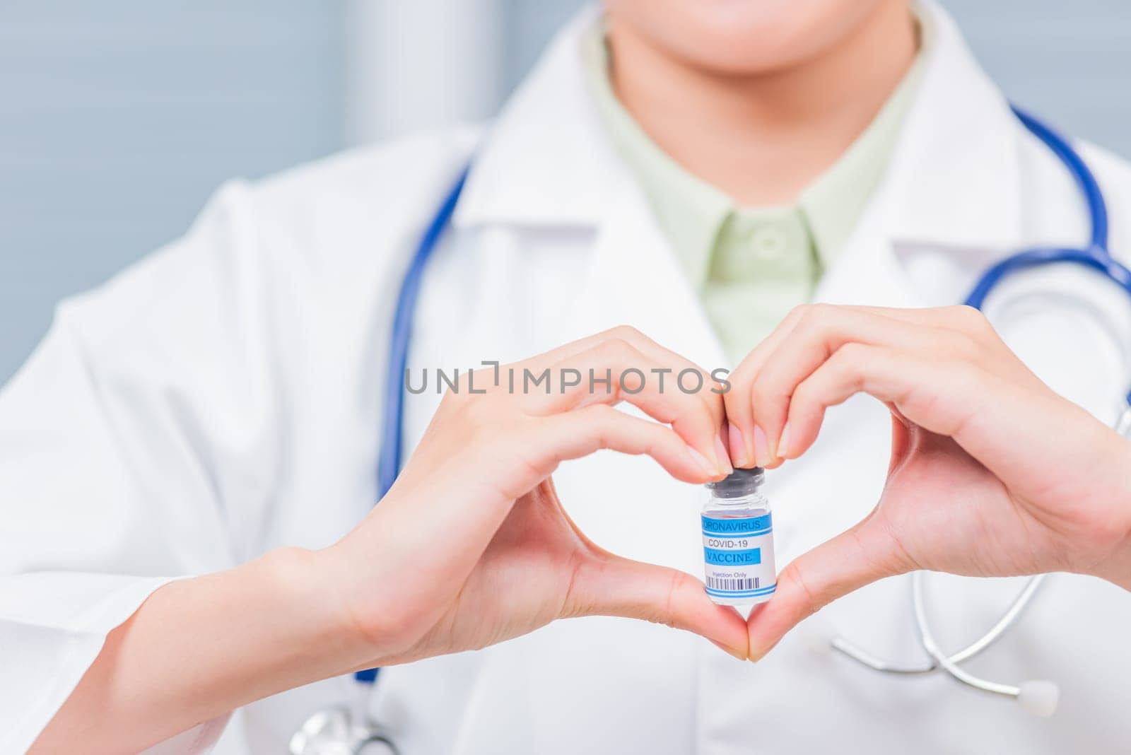 Closeup woman doctor smile forming a heart with her hands mark heart finger showing a glass vial of coronavirus vaccine, COVID-19 Medicine And Health Care Concept