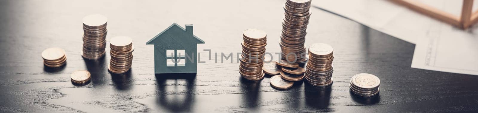 Model of a house and stacks of the coins on the black table. Concept of the planning for buying and ownership by appartment, building and renting.