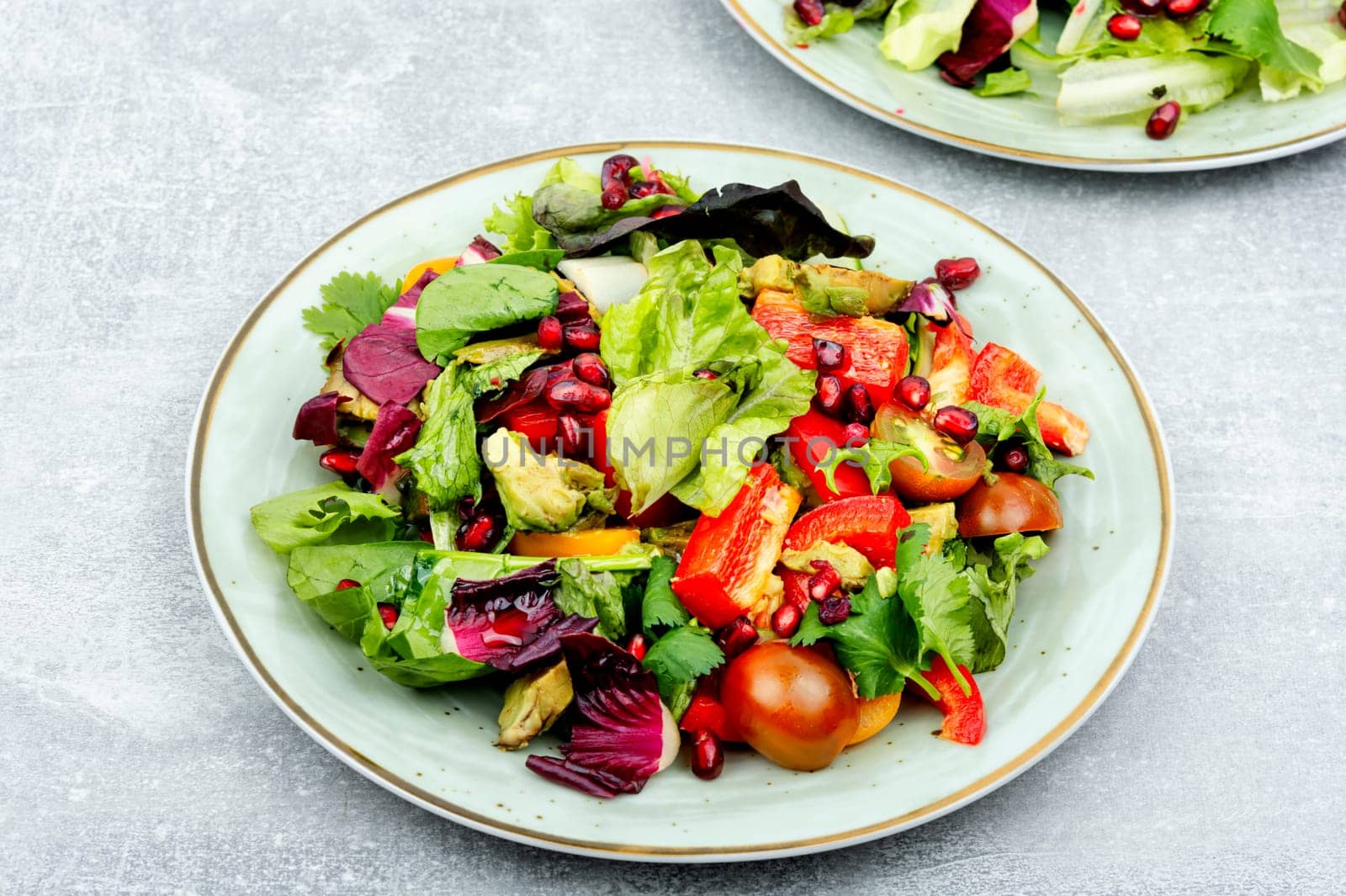 Vitamin salad with greens, pepper, red lettuce and cucumber, decorated with pomegranate.